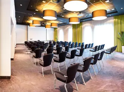 a conference room with rows of chairs and a screen at Park Inn by Radisson Leuven in Leuven