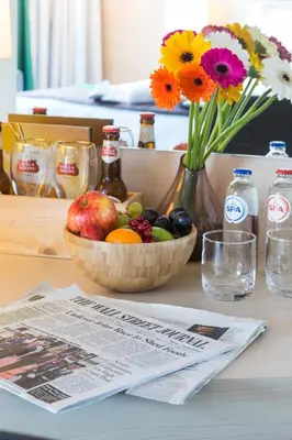 a bowl of fruit and flowers on a table with a newspaper at Park Inn by Radisson Leuven in Leuven