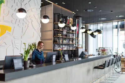 a woman sitting at a bar in a restaurant at Park Inn by Radisson Leuven in Leuven