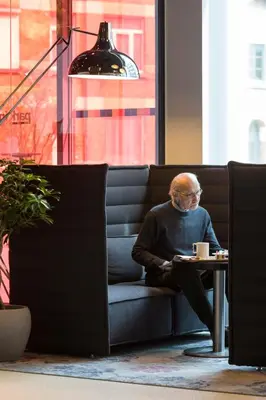an older man sitting on a couch with a table at Park Inn by Radisson Leuven in Leuven