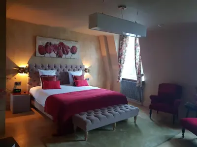 a bedroom with a large bed with red sheets and a window at Notarishuis Beveren B&B in Beveren