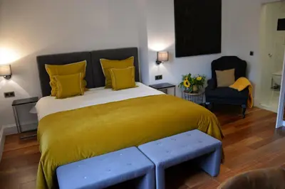 a bedroom with a large bed with a yellow blanket at Notarishuis Beveren B&B in Beveren