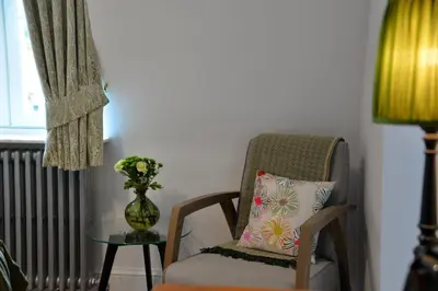 a chair with a pillow and a table with a vase at Notarishuis Beveren B&B in Beveren