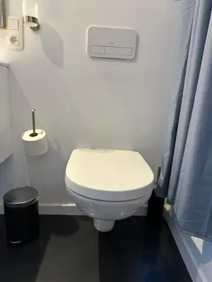 a bathroom with a white toilet and a blue shower curtain at Dokstudio50 in Ghent