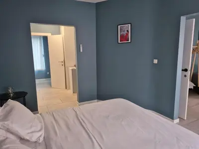 a bedroom with a white bed and a blue wall at Dokstudio50 in Ghent