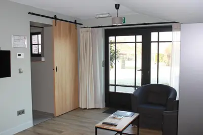 a living room with a chair and a table at B&B de Rijcke Rust in Rijkevorsel