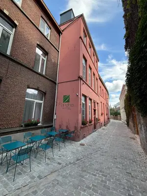 a street with tables and chairs in front of a pink building at Flandria Hotel Gent Centrum in Ghent