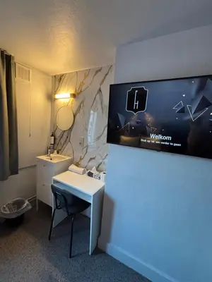 a room with a bathroom with a desk and a tv at Flandria Hotel Gent Centrum in Ghent