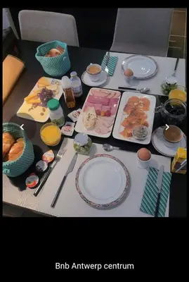 a table with plates of food and utensils on it at BnB Antwerp Centrum in Antwerp