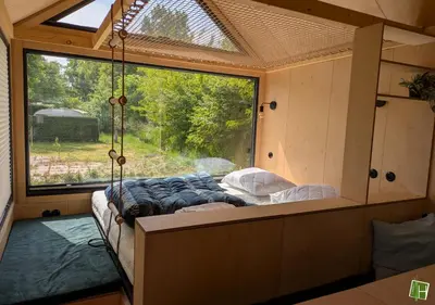a bed in a room with a large window at Camping Houtum in Kasterlee