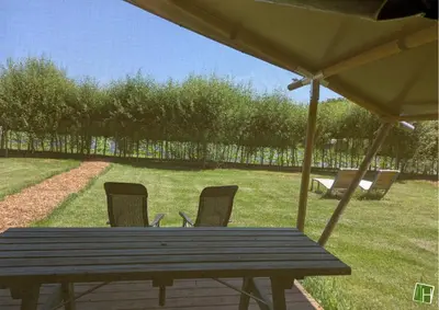 a wooden picnic table with chairs and an umbrella at Camping Houtum in Kasterlee