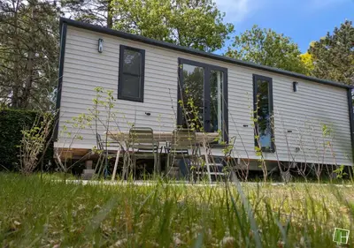 a small white house with two chairs in a field at Camping Houtum in Kasterlee