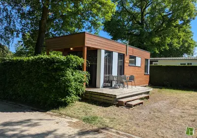 a tiny house with a porch and a table and chairs at Camping Houtum in Kasterlee