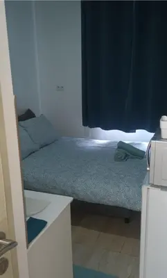 a small bedroom with a bed and a blue curtain at Private Studio Brussels Airport in Brussels