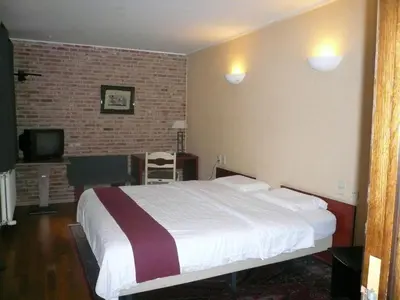 a bedroom with a large bed and a brick wall at Hotel La Barakka in Lokeren