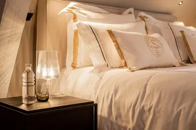 a bed with white pillows and a bottle on a table at B&B Sterckxhof in Meise
