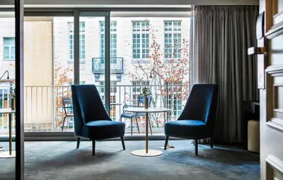a room with two chairs and a table and a balcony at Pillows Grand Boutique Hotel Reylof Ghent in Ghent