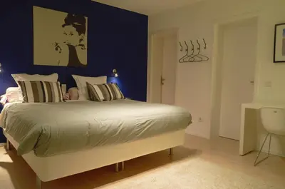 a bedroom with a large bed with a blue wall at Nena Guesthouse in Leuven
