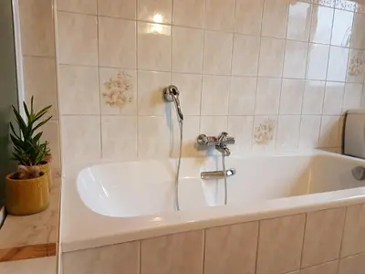 a white bath tub with a faucet in a bathroom at Gastenkamers in vakantiewoning CasaCuriosa in Mol