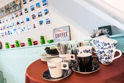 a table with coffee cups and plates on it at Gastenkamers in vakantiewoning CasaCuriosa in Mol
