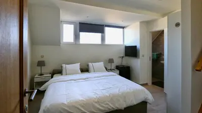 a bedroom with a large white bed with two windows at B&B Handelshof in Lier