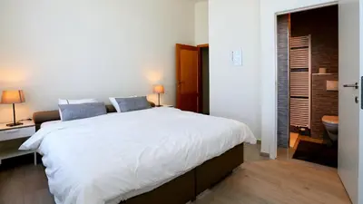 a bedroom with a large white bed and a bathroom at B&B Handelshof in Lier