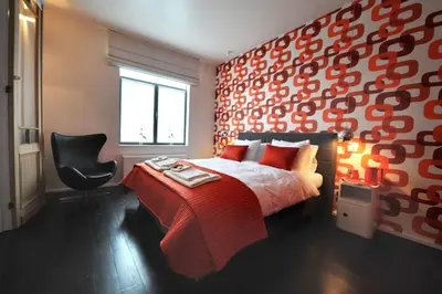 a bedroom with a red bed and a black chair at B&B Kava in Antwerp