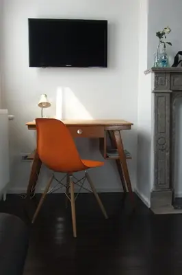 a desk with a chair and a television on a wall at B&B Kava in Antwerp