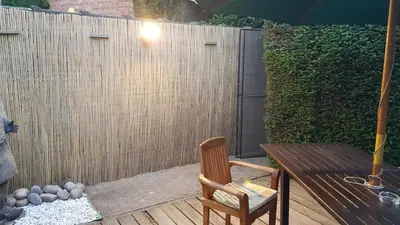 a patio with a wooden table and a wooden fence at Albert - Rooms in Mechelen