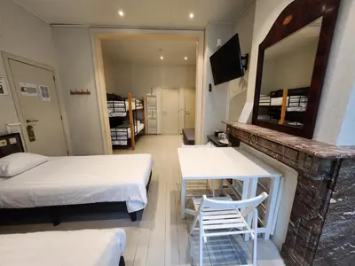 a room with two beds and a table and a mirror at Albert - Rooms in Mechelen
