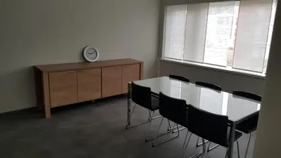 a dining room with a table and chairs and a clock at Mathilda - apartments in Grobbendonk