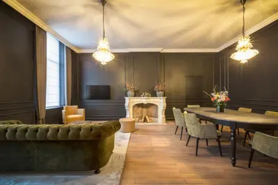 a living room with a fireplace and a table and chairs at Logement Den Beer in Meerhout