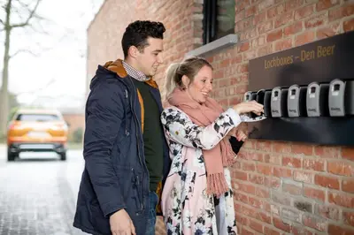 a man and a woman standing next to a brick wall at Logement Den Beer in Meerhout