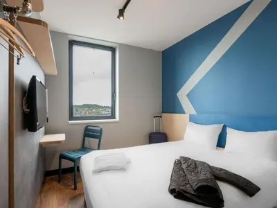 a bedroom with a white bed and a blue wall at ibis budget Leuven Centrum in Leuven