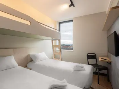 a hotel room with two beds and a tv at ibis budget Leuven Centrum in Leuven