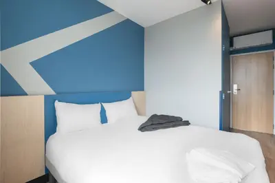 a bedroom with a white bed and a blue wall at ibis budget Leuven Centrum in Leuven