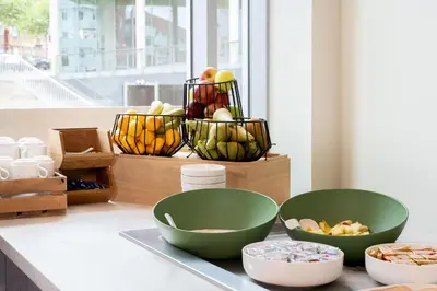 a counter with two green bowls and a basket of fruit at ibis budget Leuven Centrum in Leuven