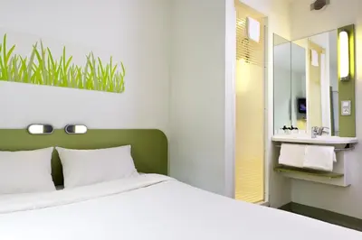 a bedroom with a white bed and a sink at ibis budget Antwerpen Centraal Station in Antwerp