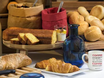 a table with bread and croissants and a blue bottle at ibis budget Hotel Brussels Airport in Diegem