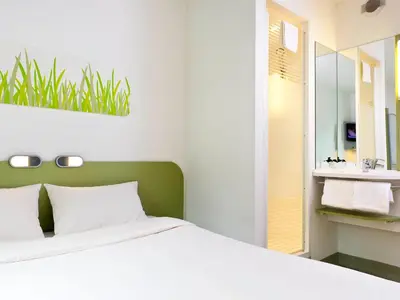 a bedroom with a white bed and a bathroom at ibis budget Hotel Brussels Airport in Diegem