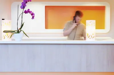 a woman talking on a cell phone on a shelf at ibis budget Hotel Brussels Airport in Diegem