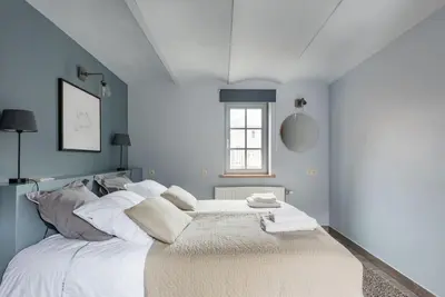 a white bed in a blue room with a window at Van Hamme 1642 - house for 2 to 4 persons in Kortenberg