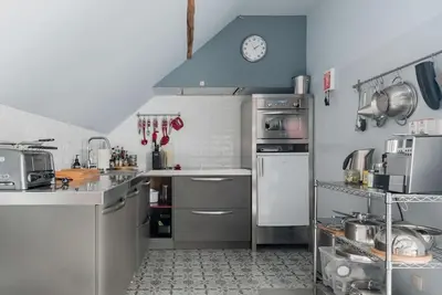 a kitchen with stainless steel appliances and a clock on the wall at Van Hamme 1642 - house for 2 to 4 persons in Kortenberg