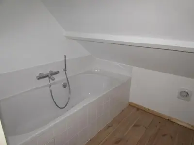 a white bath tub with a shower in a bathroom at De Spreekkamer in Hoogstraten