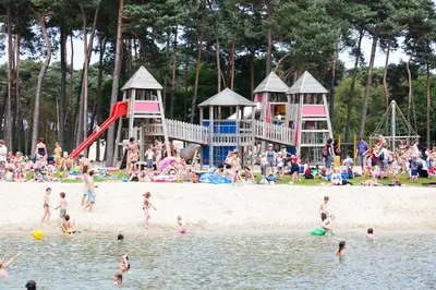 a group of people on a beach with people playing in the water at De Spreekkamer in Hoogstraten
