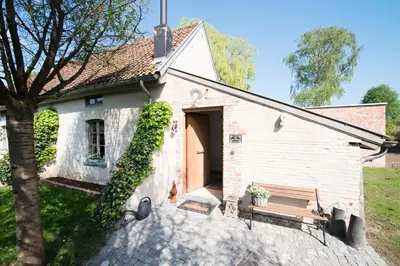 a small white building with a dog sitting in front of it at B&B De Hanewijkhoeve in Werchter