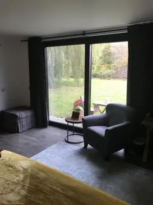a bedroom with a chair and a large window at B&B De Hanewijkhoeve in Werchter