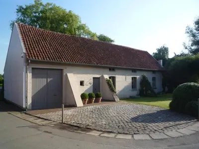 a white house with a garage on a driveway at B&B De Hanewijkhoeve in Werchter