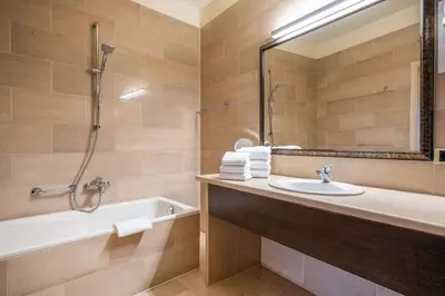 a bathroom with a sink and a tub and a mirror at Hotel Opera Antwerpen Centrum in Antwerp