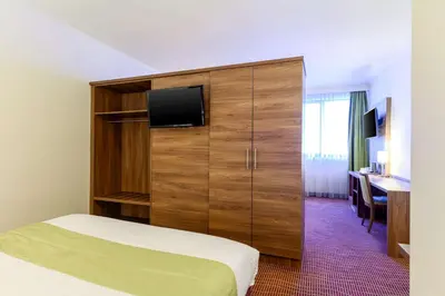a hotel room with a bed and a cabinet with a television at Hotel Opera Antwerpen Centrum in Antwerp